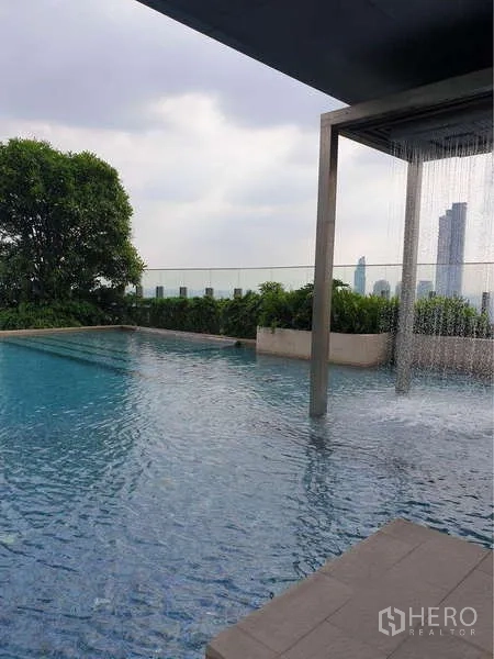 Condominium for rent in Sathon, Bangkok - Rooftop pool with water curtain feature, landscaping and skyline backdrop.