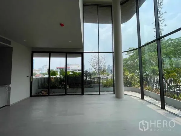 Condominium for sale in Phaya Thai, Bangkok - Open-plan living space with panoramic glass walls and access to a landscaped balcony.