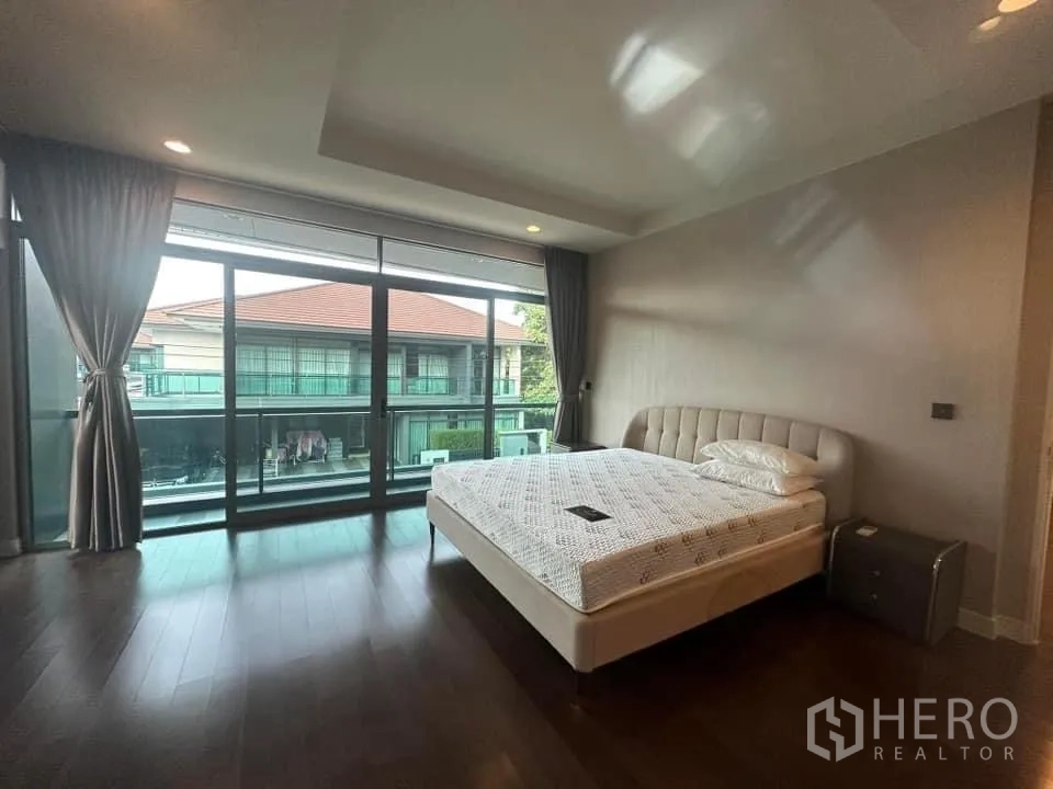 Detached House for rent in Bang Kapi, Bangkok - Primary bedroom with king bed, wall-to-wall windows and balcony view.