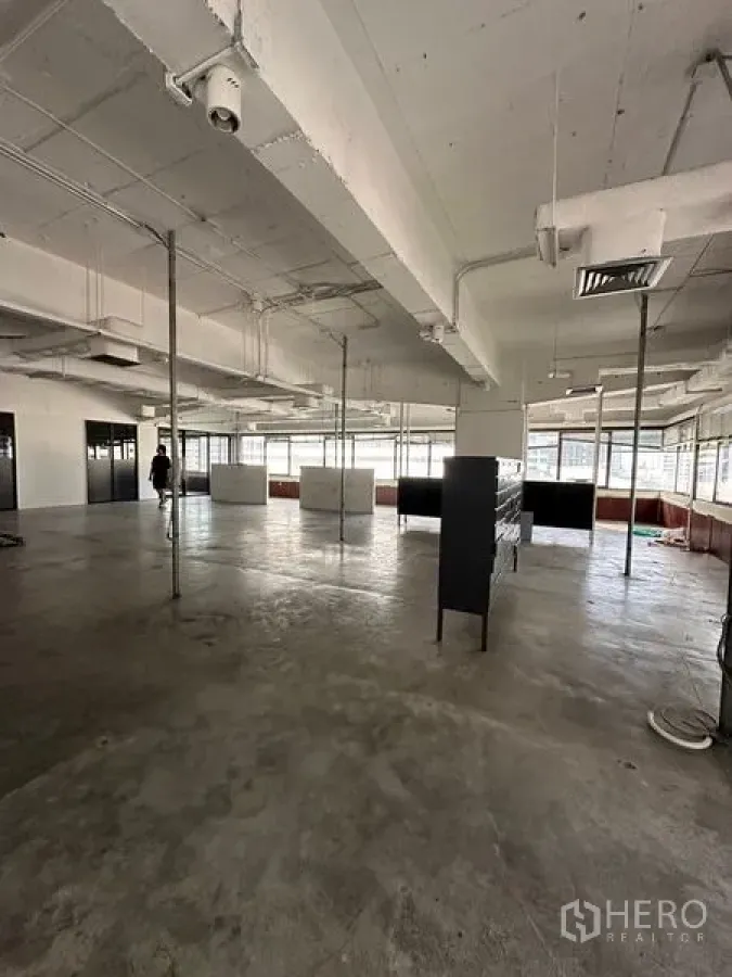 Office Space for rent in Watthana, Bangkok - Spacious open-plan office with exposed ceiling, concrete floors, and large windows providing city light.