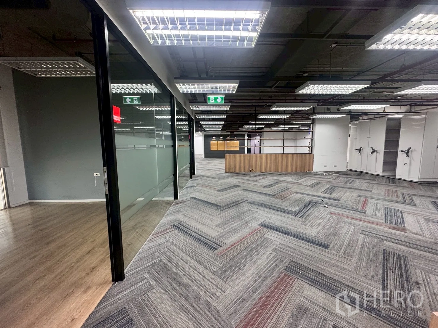 办公室 for rent in Watthana, Bangkok - 玻璃分隔的走道连接至开放式办公区，铺设地毯砖与顶灯。