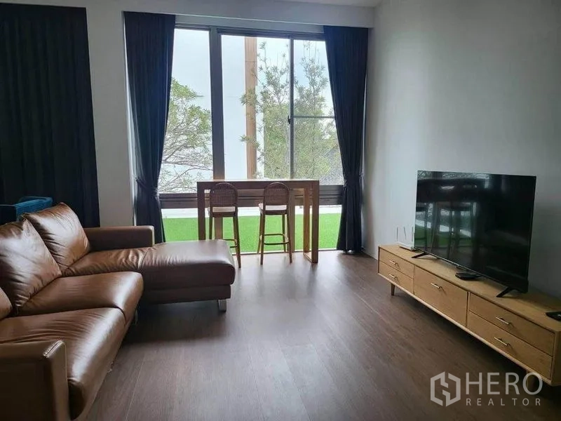 บ้าน ให้เช่าในSaphan Sung, Bangkok - ห้องนั่งเล่นสว่าง โซฟาหนัง ตู้วางทีวี และโต๊ะบาร์ริมหน้าต่างบานใหญ่ วิวสีเขียว