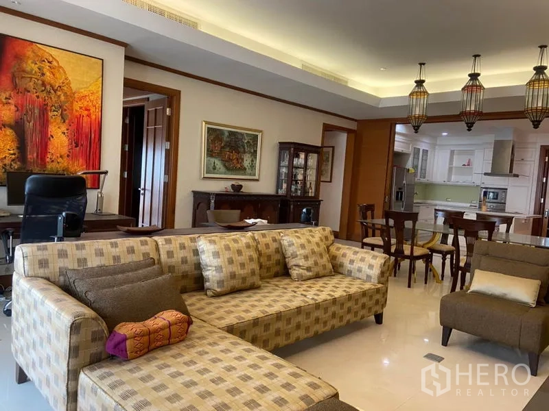 公寓 出租在Sathon, Bangkok - 从客厅望向厨房与餐区，花纹沙发、玻璃柜与吊灯。