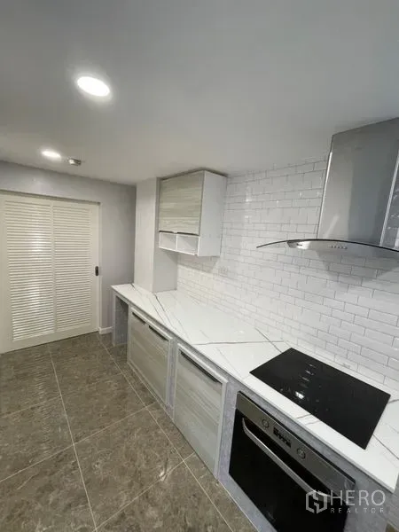 คอนโด ให้เช่าหรือขายในWatthana, Bangkok - ครัวปิด ผนังกระเบื้องลายอิฐสีขาว เคาน์เตอร์ลายหินอ่อน พร้อมเตาอบและเครื่องดูดควันสแตนเลส