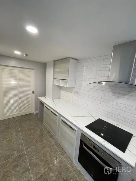 คอนโด ให้เช่าหรือขายในWatthana, Bangkok - ครัวปิด ผนังกระเบื้องลายอิฐสีขาว เคาน์เตอร์ลายหินอ่อน พร้อมเตาอบและเครื่องดูดควันสแตนเลส