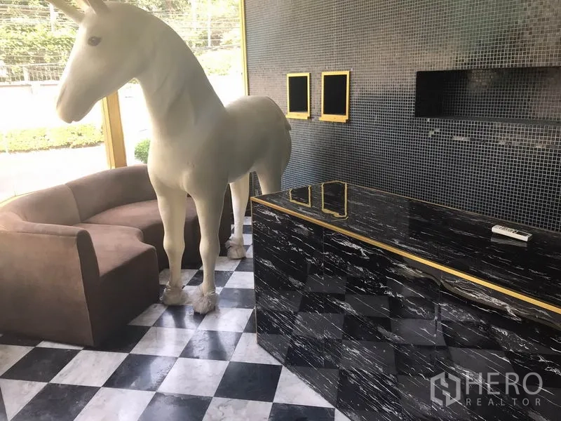 零售空间 出租在Watthana, Bangkok - 室内黑白棋盘地砖，配有沙发与可展示的吧台区域。