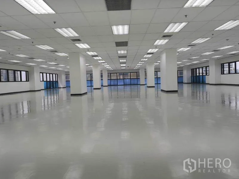 办公空间 出租在Phaya Thai, Bangkok - 宽敞开放式办公楼层，亮面地坪、栅格吊顶灯、白色立柱与环窗采光。