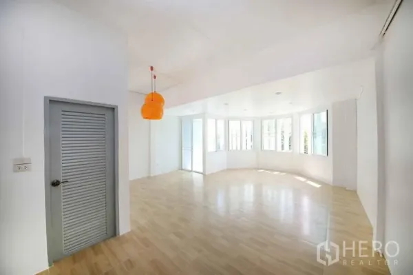 店屋 出租在Wang Thonglang, Bangkok - 转角开放空间，弧形窗、木纹地砖与橙色吊灯。