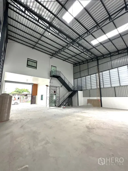 Warehouse for rent or sale - Warehouse interior facing the entry with steel staircase and tall truss roof.
