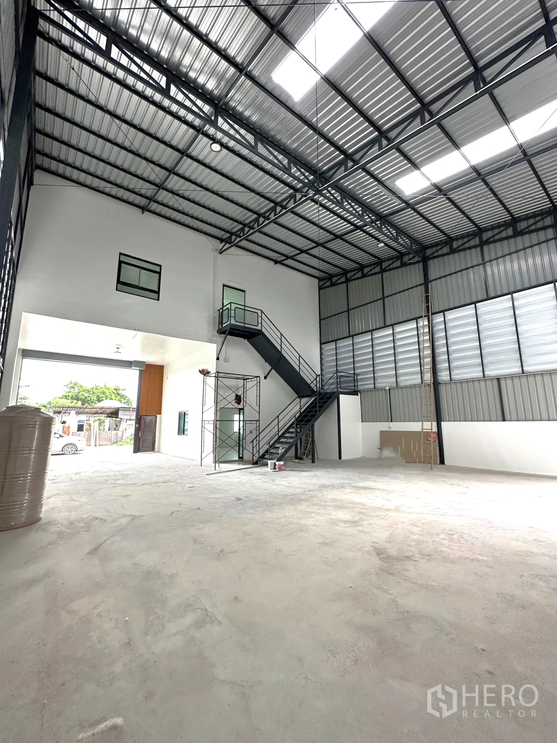 Warehouse for rent or sale - Warehouse interior facing the entry with steel staircase and tall truss roof.