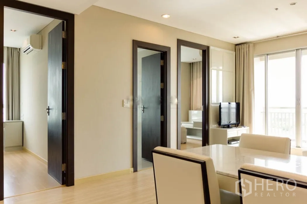 คอนโด ให้เช่าในRatchathewi, Bangkok - ทางเดินสู่สองห้องนอน ประตูไม้สีเข้ม มุมวางทีวีติดระเบียงกระจก