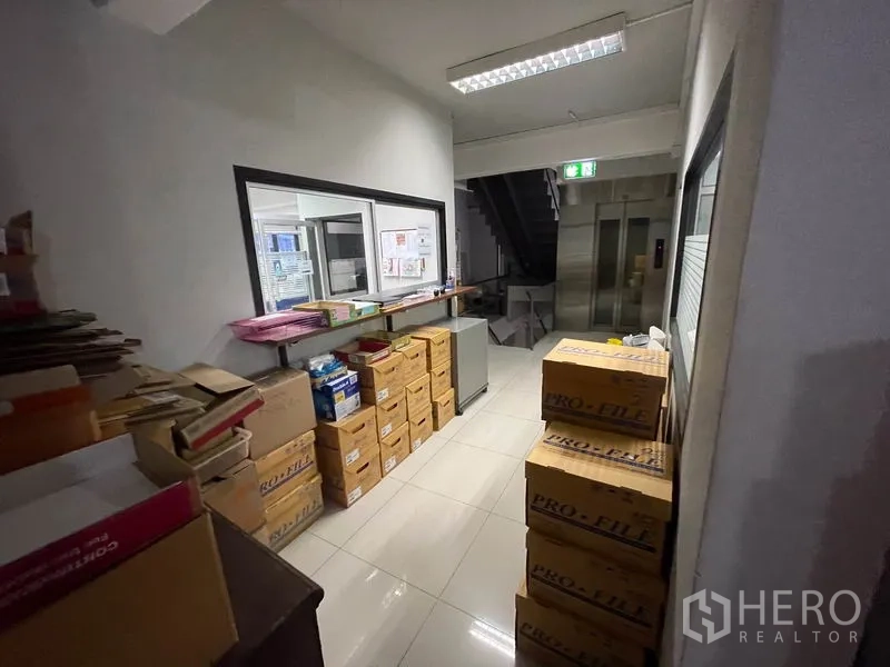 Office Space for rent in Khlong Toei, Bangkok - Storage corridor with stacked archive boxes, service window and glossy tile floor.