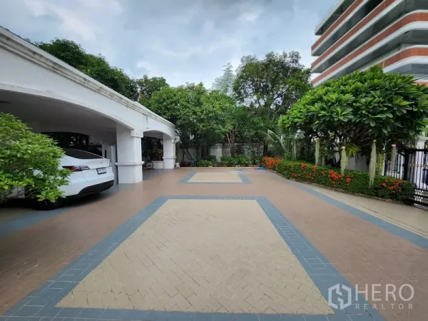 独立式住宅 出租在Prawet, Bangkok - 宽敞的铺砖前院与花带，旁侧设有多车位的有顶车库。