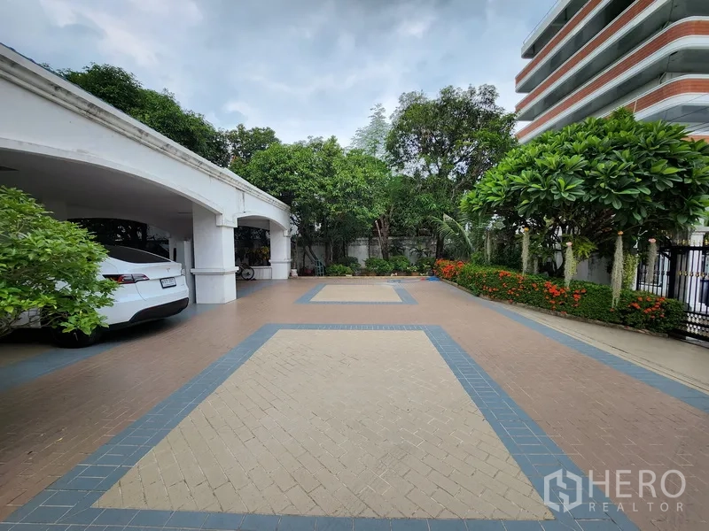 独立式住宅 出租在Prawet, Bangkok - 宽敞的铺砖前院与花带，旁侧设有多车位的有顶车库。