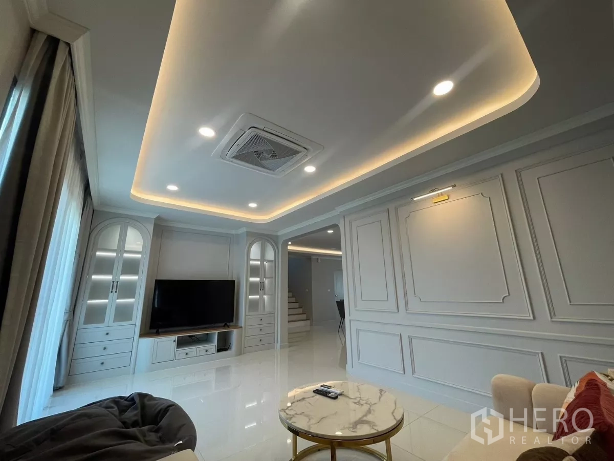 独立式住宅 出租在Bang Phli, Samut Prakan - 客厅明亮，灯槽天花、电视背景柜与大窗户。