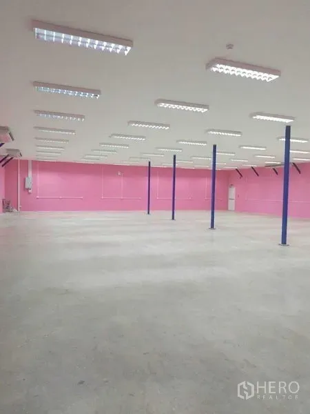 Warehouse for rent in Khlong Luang, Pathum Thani - Open-plan warehouse interior with LED lighting, blue columns and concrete floor.