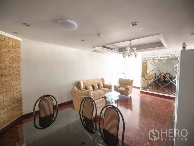 Condominium for rent in Watthana, Bangkok - Bright living and dining area with parquet floors, beige sofas, chandelier, and a mirrored feature wall.