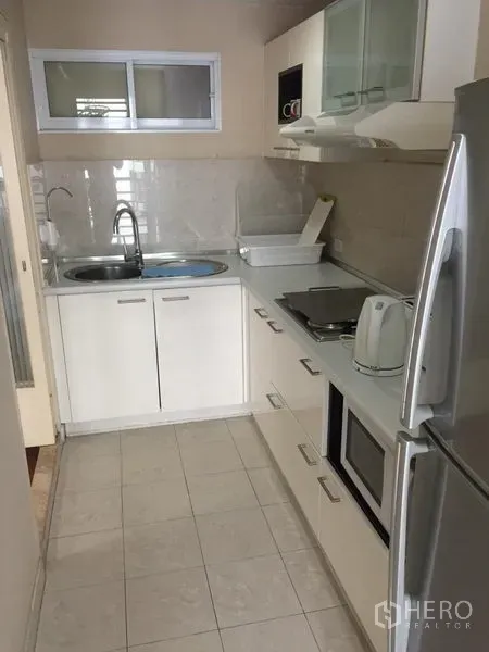 คอนโด ให้เช่าในWatthana, Bangkok - ครัวแบบแกลลีย์พร้อมตู้สีขาว อ่างล้างมือ เตา ไมโครเวฟ และตู้เย็นขนาดใหญ่