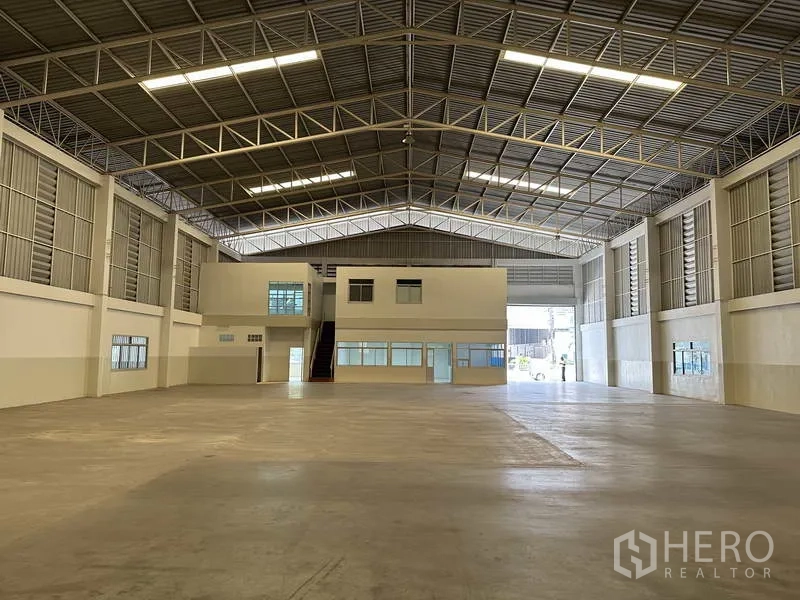 工厂 出租在Samut Prakan - 开阔库房，内部两层办公室与宽幅卷门便于卡车进出。