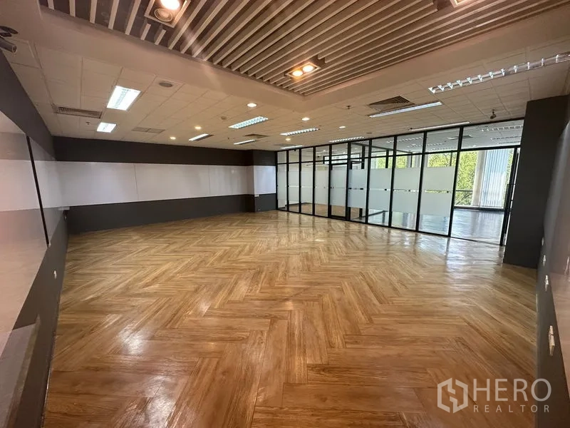 Office Space for rent - Large herringbone-floored room with feature ceiling panels and glass partitions.