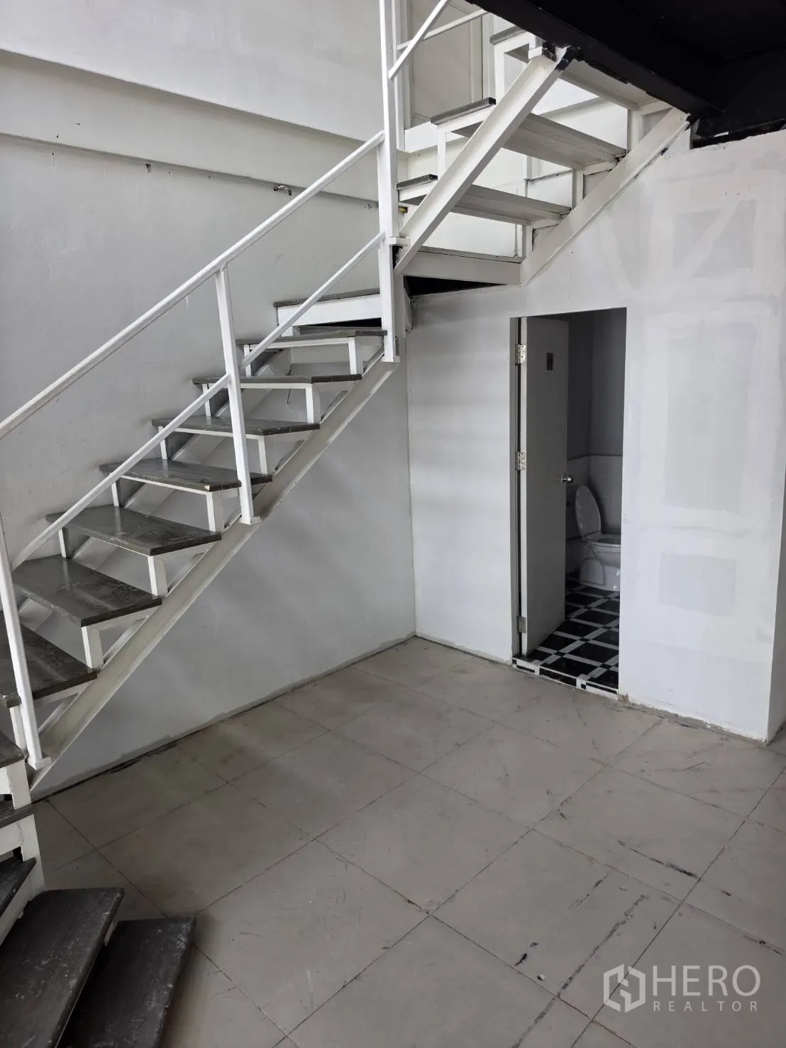 Retail Space for rent in Watthana, Bangkok - Interior corner with a white metal staircase and a restroom beneath the stairs.
