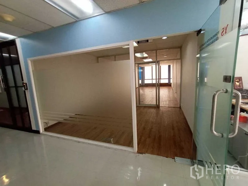 Office Space for rent - Glass-door entrance from corridor into office with partitions and wood floors.