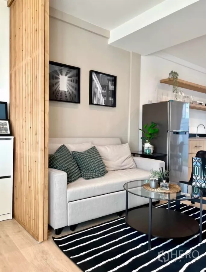 联排别墅 出租在Prawet, Bangkok - 舒适沙发角，圆形玻璃茶几，旁为不锈钢冰箱与置物架。