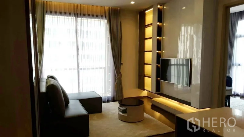 คอนโด ให้เช่าในWatthana, Bangkok - ห้องนั่งเล่นโปร่งสว่างด้วยม่านหน้าต่างเต็มบาน ผนังทีวีพร้อมชั้นไฟซ่อน