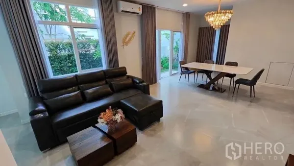 บ้าน ให้เช่าในPrawet, Bangkok - ห้องนั่งเล่นและรับประทานอาหารแบบโอเพ่นพลัน โซฟาหนัง โคมแชนเดอเลียร์ และประตูกระจกสไลด์สู่สวน