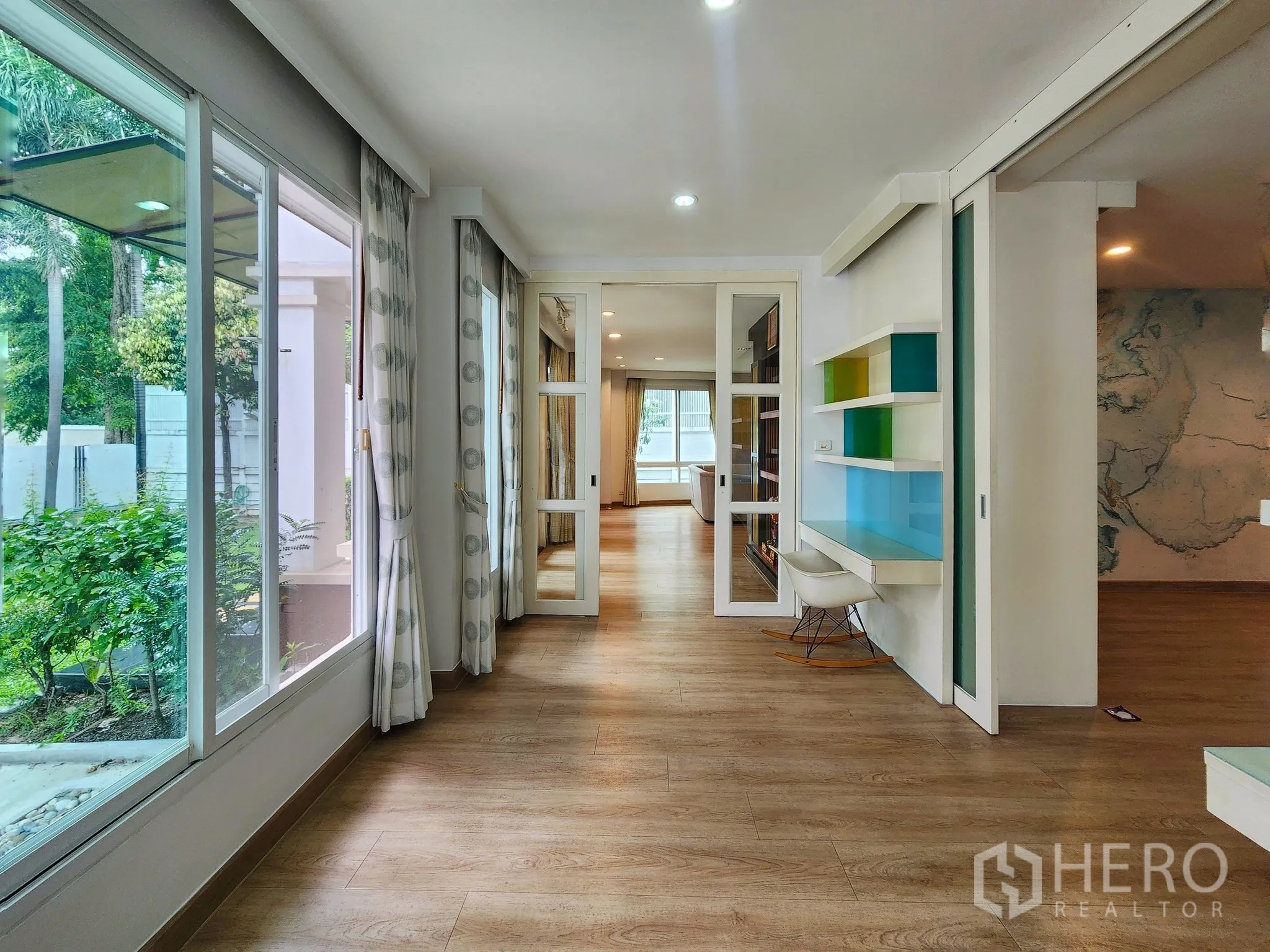 独立式住宅 出租在Bang Kapi, Bangkok - 玻璃走廊，内置书桌与彩色搁架，眺望花园。