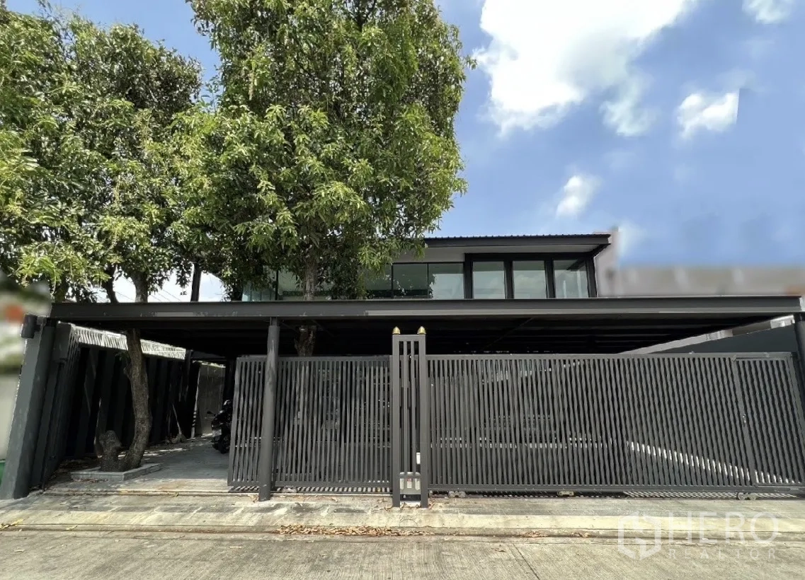 บ้าน ให้เช่าหรือขายในPhra Khanong, Bangkok - บ้านเดี่ยวสไตล์โมเดิร์นย่านพระโขนง กรุงเทพฯ หน้าบ้านมีต้นไม้ใหญ่และรั้วเหล็กสีดำ