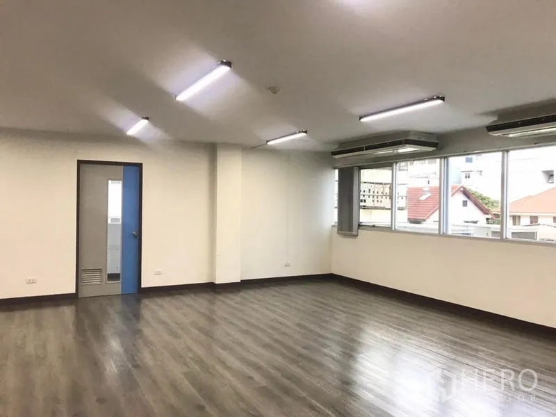 Office Space for rent in Bangkok Noi, Bangkok - Open workspace with blue‑trim door, neighborhood views from windows, and bright lighting.