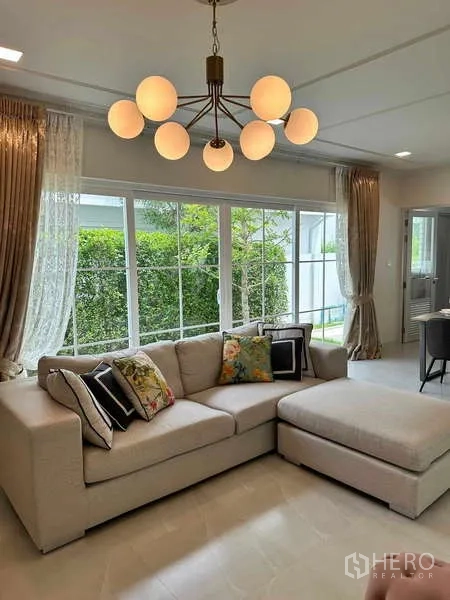 Detached House for sale in Bang Phli, Samut Prakan - Living room with L-shaped sofa, chandelier and garden views