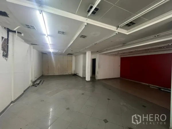 店屋 出租在Watthana, Bangkok - 宽敞的空置室内空间，立柱、轨道照明和亮面地砖，适合展厅或零售。