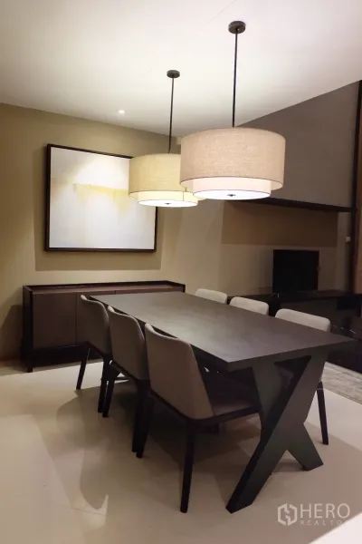 Condominium for rent in Sathon, Bangkok - Dining area with six-seat dark-wood table and twin pendant lights beside a media console.