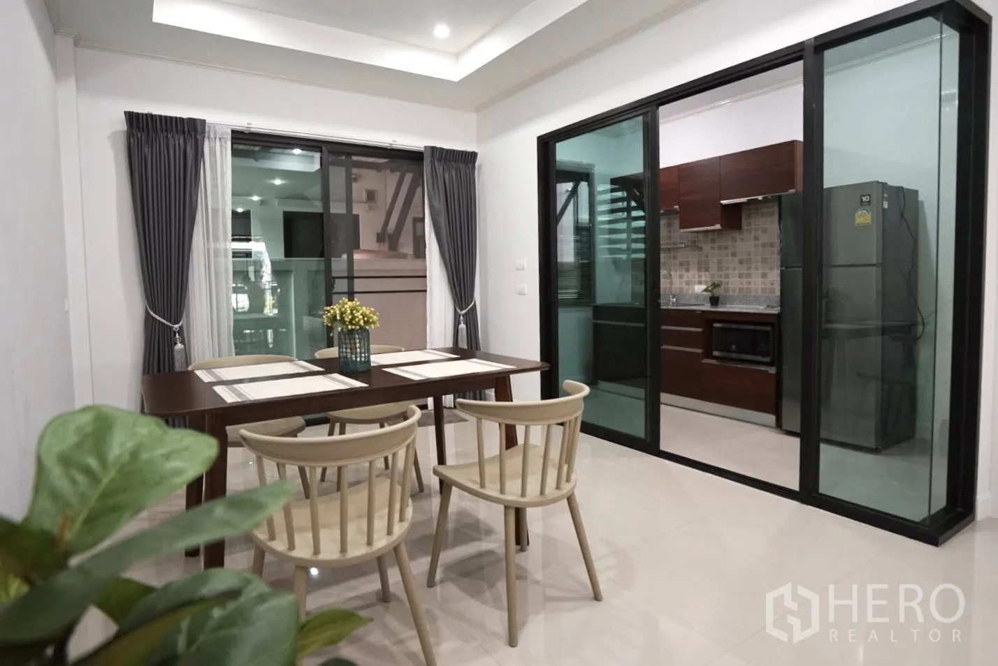 Townhouse for rent in Bang Kapi, Bangkok - Dining area with four chairs and table next to sliding glass doors separating the kitchen.