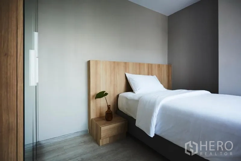 อพาร์ทเมนท์ ให้เช่าในKhlong Toei, Bangkok - ห้องนอนรอง เตียงเดี่ยว หัวเตียงไม้ โทนสีเทาอบอุ่น