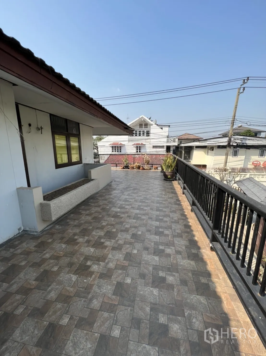 Home Office for rent in Watthana, Bangkok - Spacious tiled rooftop terrace with railing and neighborhood views.