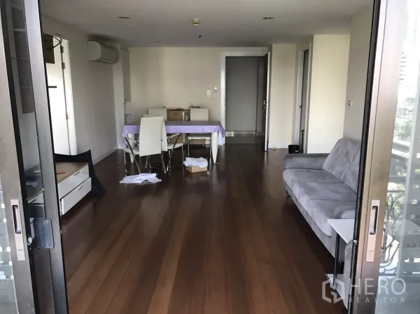 คอนโด ให้เช่าหรือขายในWatthana, Bangkok - ห้องนั่งเล่นแบบโอเพ่นมีพื้นไม้ โซฟาสีเทาและชุดทานอาหาร มุมมองจากระเบียง.