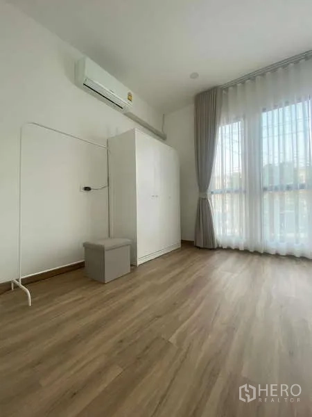 Townhouse for rent in Bang Kapi, Bangkok - Spare room with white wardrobe, air conditioner and tall curtained window.