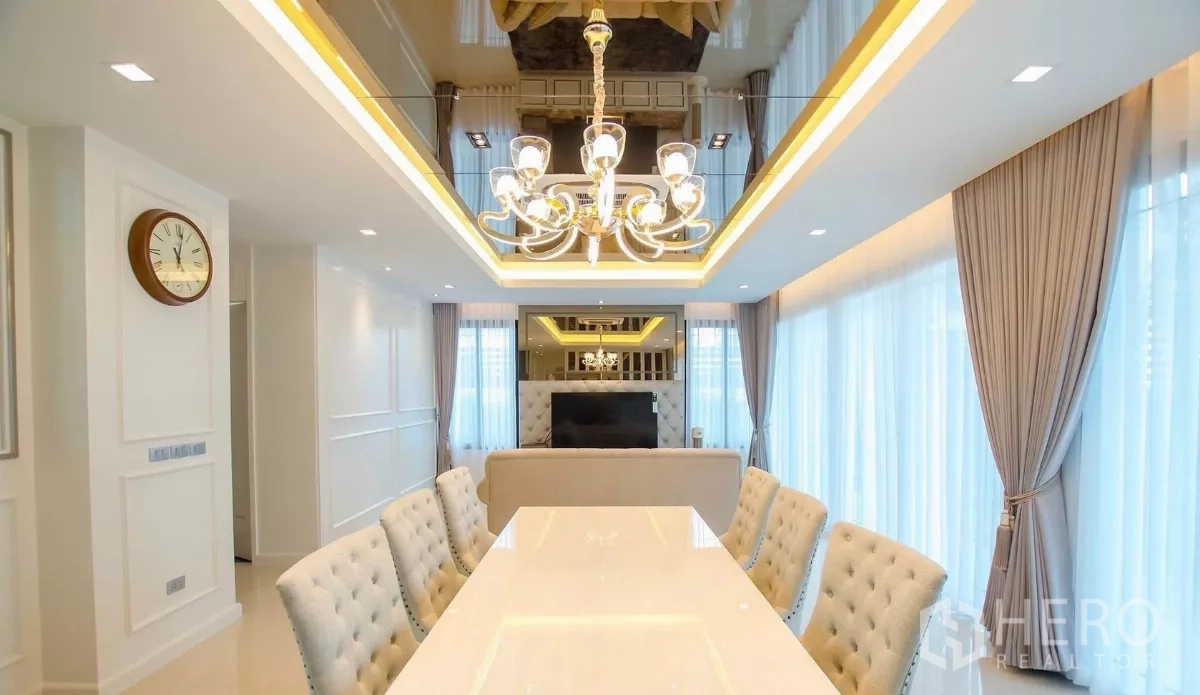 Detached House for rent in Bang Bon, Bangkok - Long dining table under a chandelier facing the sofa and TV feature wall.