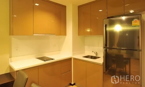 คอนโด ให้เช่าในKhlong Toei, Bangkok - ครัวแพนทรีขนาดกะทัดรัด ตู้บานเงา เตาไฟฟ้า และตู้เย็นสแตนเลส ภายในคอนโดย่านสุขุมวิท