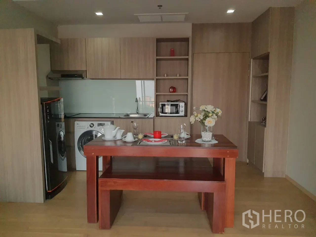 คอนโด ให้เช่าในWatthana, Bangkok - ครัวแบบเปิดตู้ไม้โทนอ่อน แผงกระจก และโต๊ะกินข้าวตรงกลาง