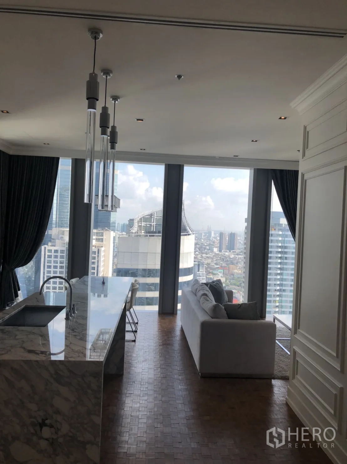 คอนโด ให้เช่าในBang Rak, Bangkok - โถงนั่งเล่นแบบโอเพ่นแปลน พร้อมครัวไอส์แลนด์หินอ่อน โคมไฟแขวน และโซฟา วิวเมือง