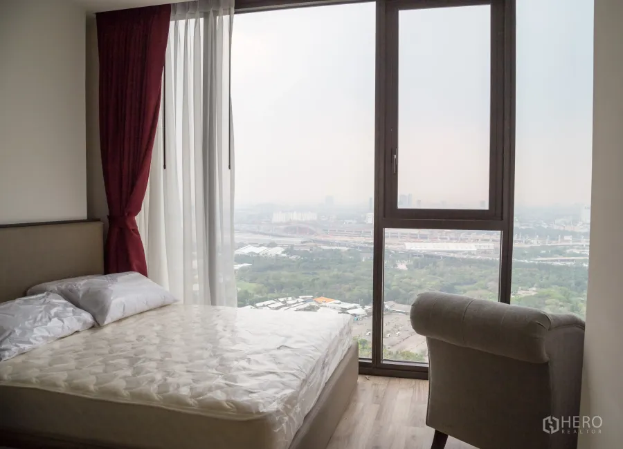 คอนโด ให้เช่าในChatuchak, Bangkok - ห้องนอนสว่างพร้อมหน้าต่างเต็มบานและวิวเมือง–สวนในคอนโดจตุจักร