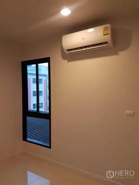 店屋 出租或出售在Bang Na, Bangkok - 卧室一角，窗户与壁挂式空调。