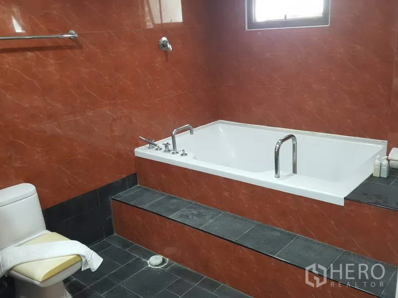 คอนโด ให้เช่าในWatthana, Bangkok - ห้องน้ำพร้อมอ่างอาบน้ำใบใหญ่แบบบิวท์อินบนแท่นขั้นบันได กระเบื้องลายหินอ่อนสีส้ม และโถสุขภัณฑ์