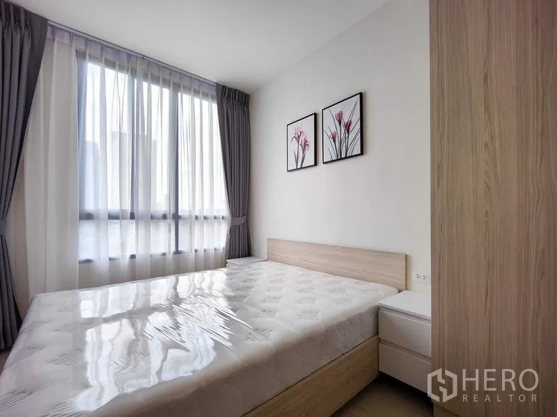 Condominium for rent - Second bedroom with large window, light-wood bedframe and floral artwork.