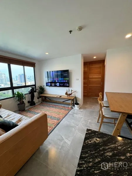 公寓 出租或出售 - 从厨房望向客厅，可见电视墙、大窗与餐桌。