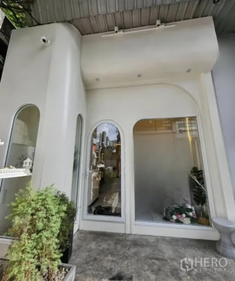 พื้นที่ขายปลีก ให้เช่าในWatthana, Bangkok - ด้านหน้าร้านโทนขาว กระจกโค้ง พร้อมกระถางต้นไม้